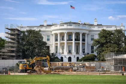 The White House with surrounding scaffolding and construction equipment under clear sky